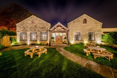 A stone building with a lawn and picnic tables.